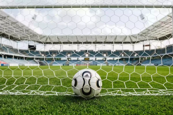 Balón de fútbol dentro de la red de una portería en un estadio italiano con gradas al fondo