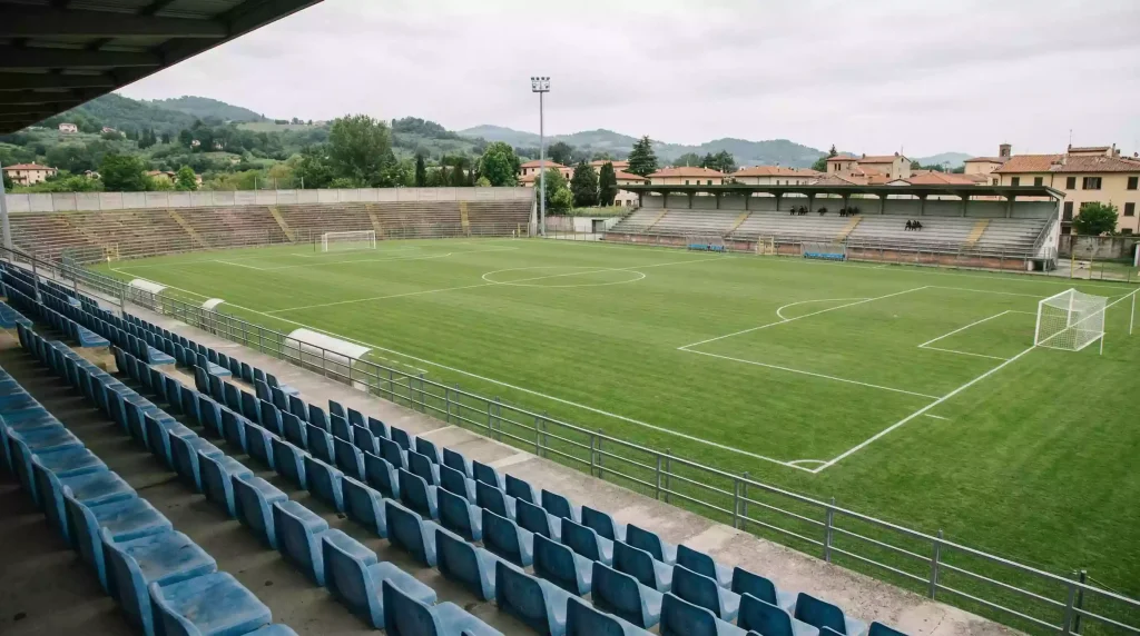 Campo de fútbol de segunda división italiana con gradas parcialmente vacías y césped natural