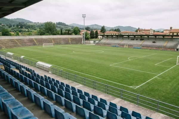 Campo de fútbol de segunda división italiana con gradas parcialmente vacías y césped natural