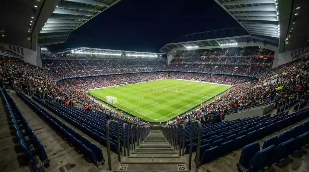 Campo de fútbol visto desde las gradas altas de un gran estadio europeo iluminado de noche