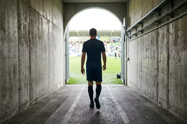 Jugador de fútbol con equipación deportiva caminando por el túnel de vestuarios hacia el campo